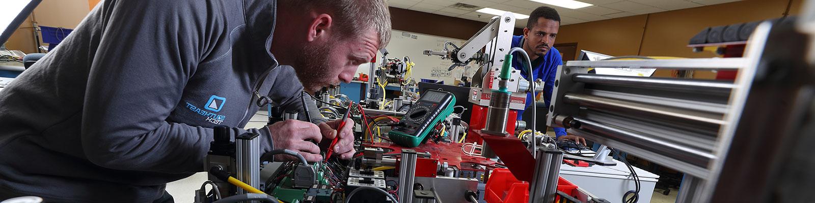 mechatronics students working on large electronic and robotic project in a classroom